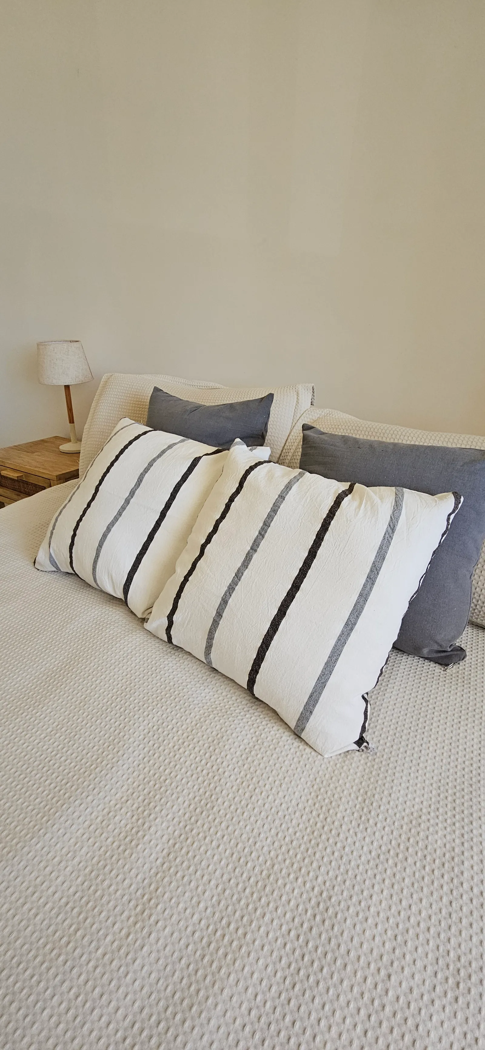 Almohadón de lino rústico blanco con rayas en negro y gris.